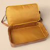 Open mustard yellow suitcase on a beige background